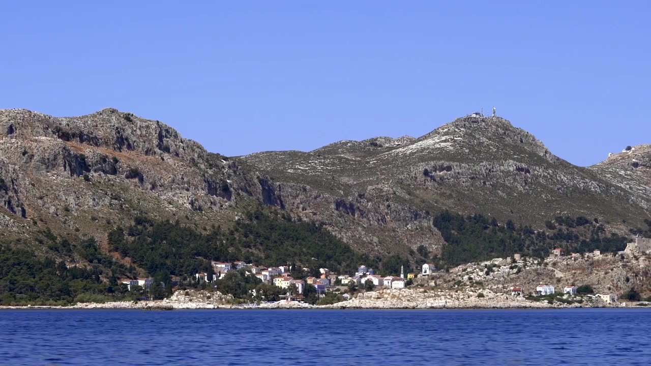Villaggio costiero annidato ai piedi di una montagna rocciosa.