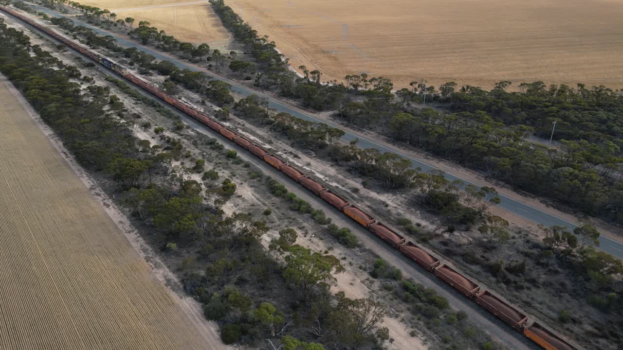 tomada de seguimiento aéreo de un largo tren de carga industrial de hierro en el ferrocarril en el campo australiano