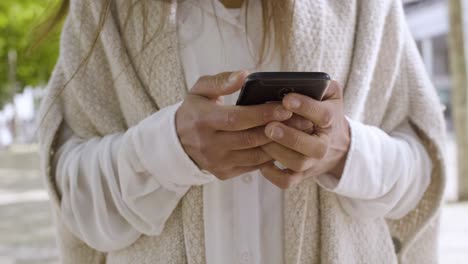 cropped shot of woman in white coat holding smartphone.