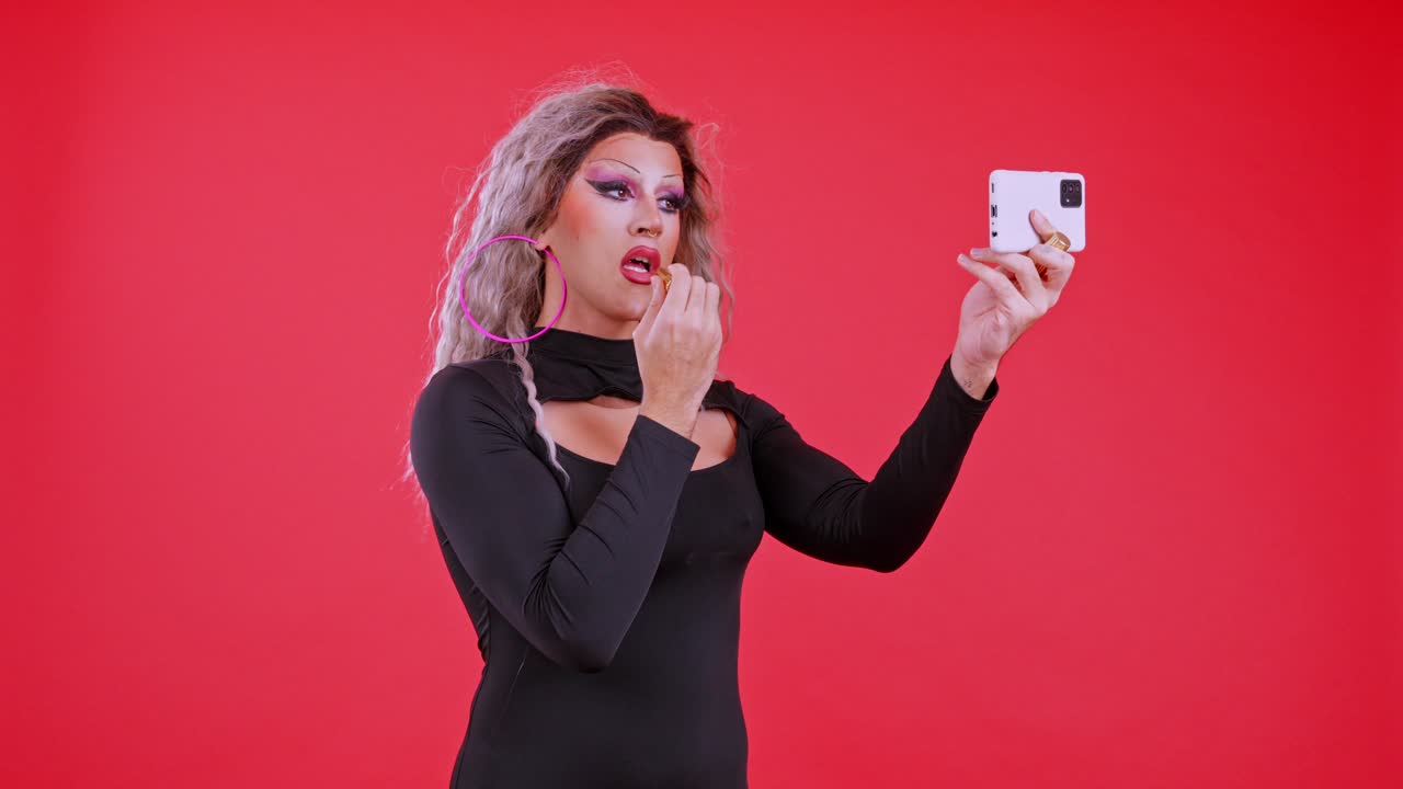 Drag Queen Applying Lipstick and Looking at Smartphone