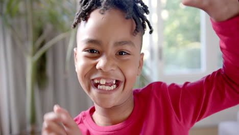 Retrato-De-Un-Feliz-Niño-Afroamericano-Al-Que-Le-Faltan-Dientes-Bailando-En-Una-Habitación-Soleada,-Cámara-Lenta