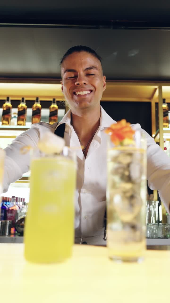 Barman sorridente presenta due cocktail colorati in un bar moderno
