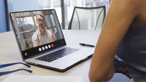 Mujer-Afroamericana-Usando-Una-Computadora-Portátil-Para-Videollamadas,-Con-Un-Colega-De-Negocios-En-La-Pantalla