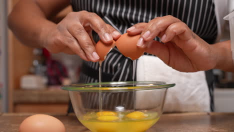 rompiendo huevos orgánicos de corral en un recipiente de vidrio para mezclarlos y agregarlos a una receta casera - vista lateral en cámara lenta