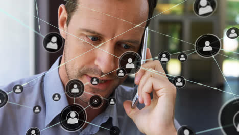 Animation-of-network-of-connections-with-icons-over-caucasian-businessman-talking-on-smartphone