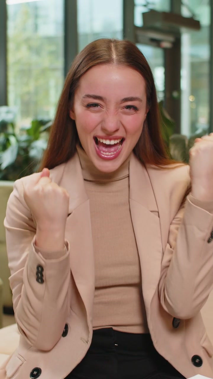 Excitata donna d'affari di successo in abiti formali che celebra il successo vittoria buone notizie nella hall dell'ufficio