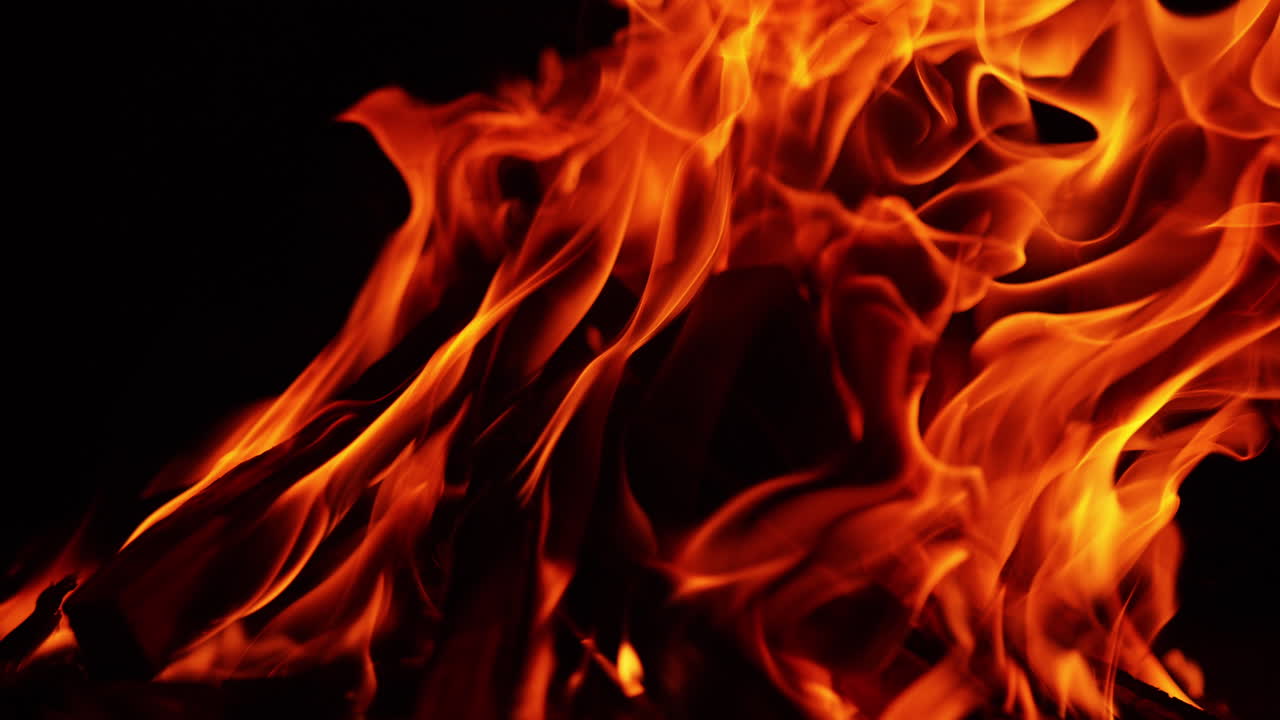 Wooden chops burn in the bonfire. Calming view of campfire isolated on black backdrop. Close up.