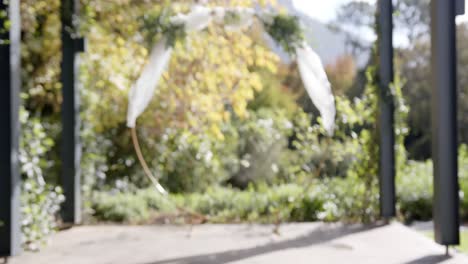 General-view-of-wedding-arch-with-decorations-and-flowers-in-sunny-garden,-copy-space,-slow-motion