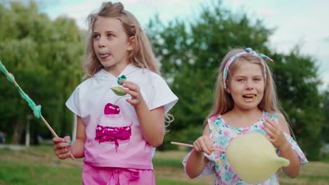 cute girls eating cotton candy. little girls eating cotton candy in the park