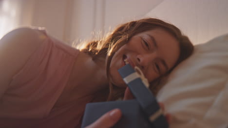una chica romántica desempaquetando un regalo en la luz del sol de la mañana en primer plano. una mujer feliz posando
