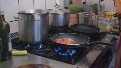 the tomatoes are swinging in the pan while flames are arising