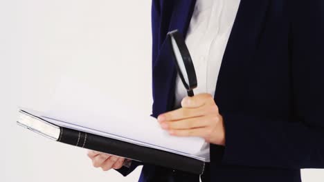 Businesswoman-checking-document-with-magnifying-glass