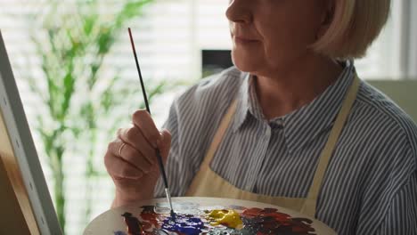 video of concentration senior female artist painting at easel