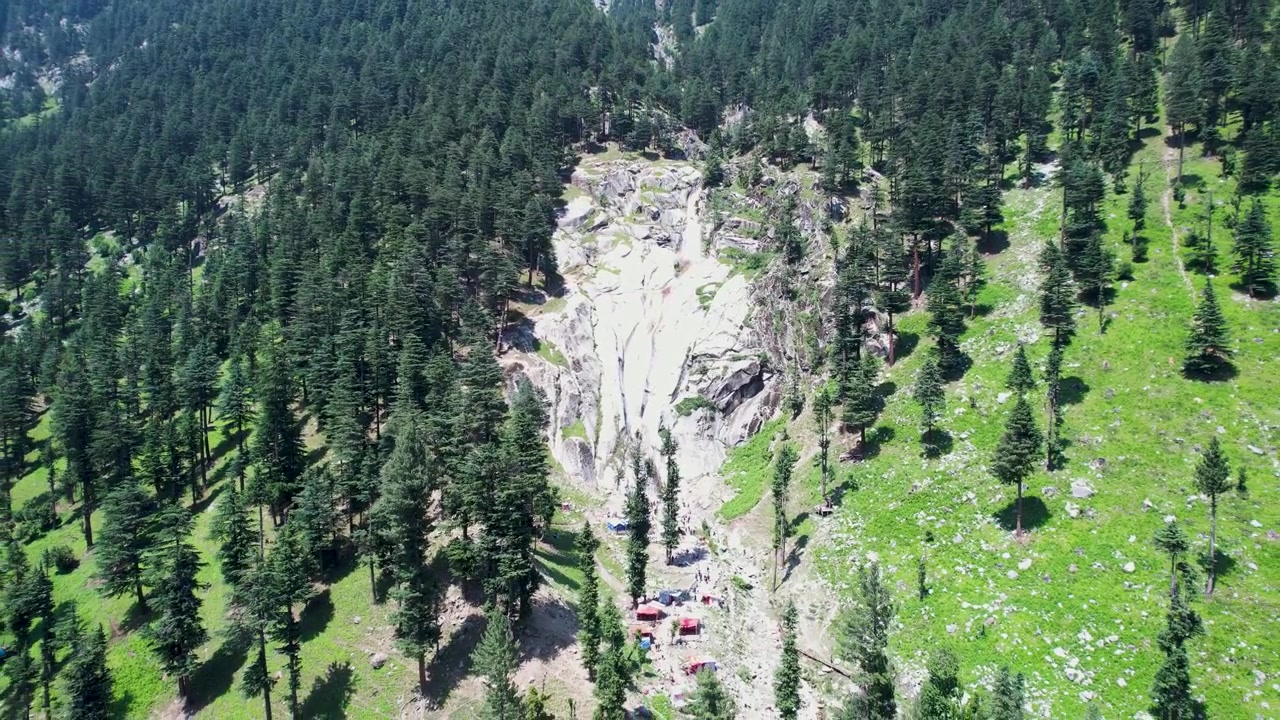 Una cascata scende attraverso scogliere rocciose circondate da una fitta foresta di conifere nel distretto di Upper Dir, Khyber Pakhtunkhwa, Pakistan