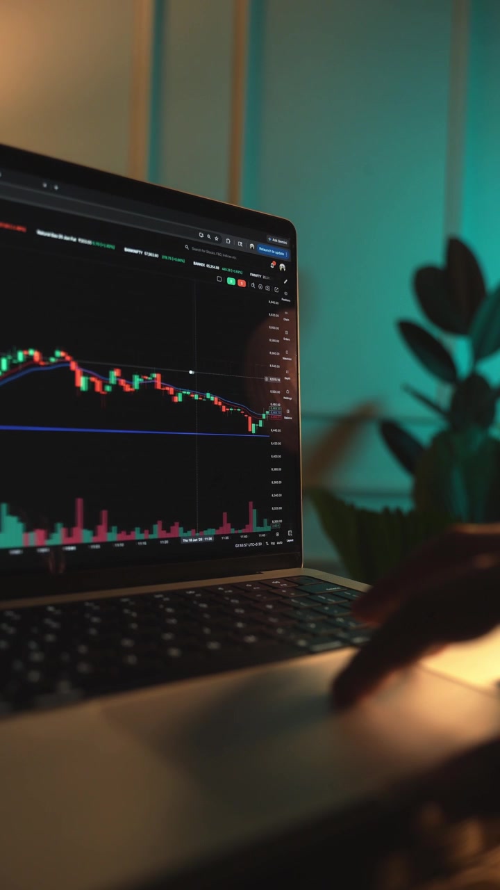 Trader che analizza grafici di borsa su un laptop tramite una piattaforma di brokeraggio