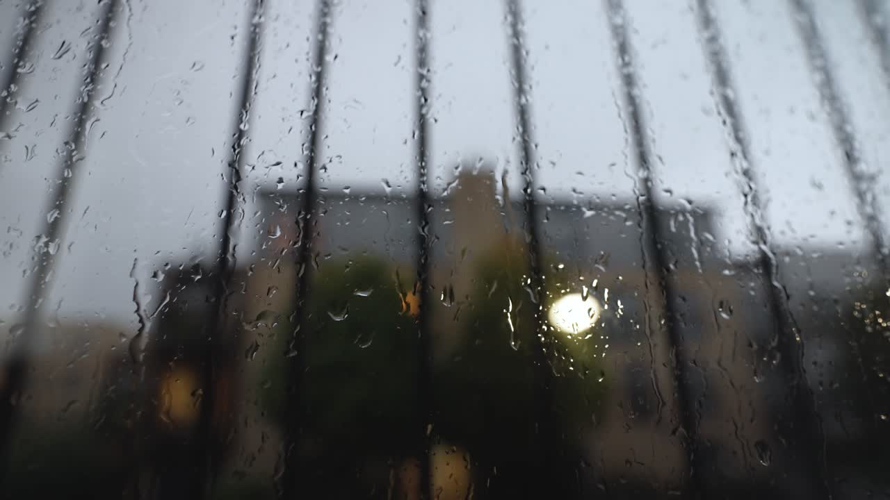 un primer plano abstracto de una ventana cubierta de gotas de lluvia, a medida que cae más lluvia, el agua corre por la ventana en un día gris oscuro y sombrío durante el relámpago de la tormenta