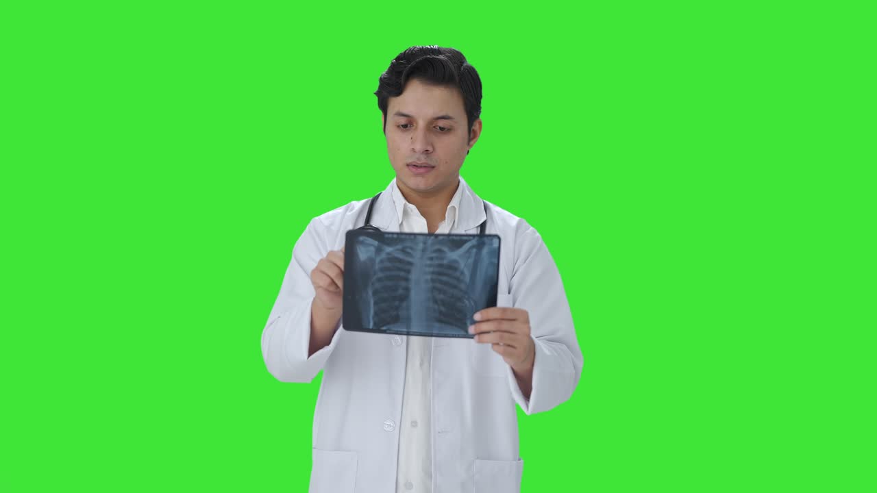 Serious Indian doctor checking X ray report Green screen