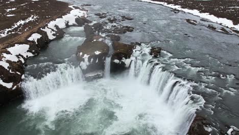 cascada escénica que fluye desde un acantilado rocoso en un día de invierno