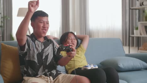 asian children with joystick game play video game on tv and celebrating victory