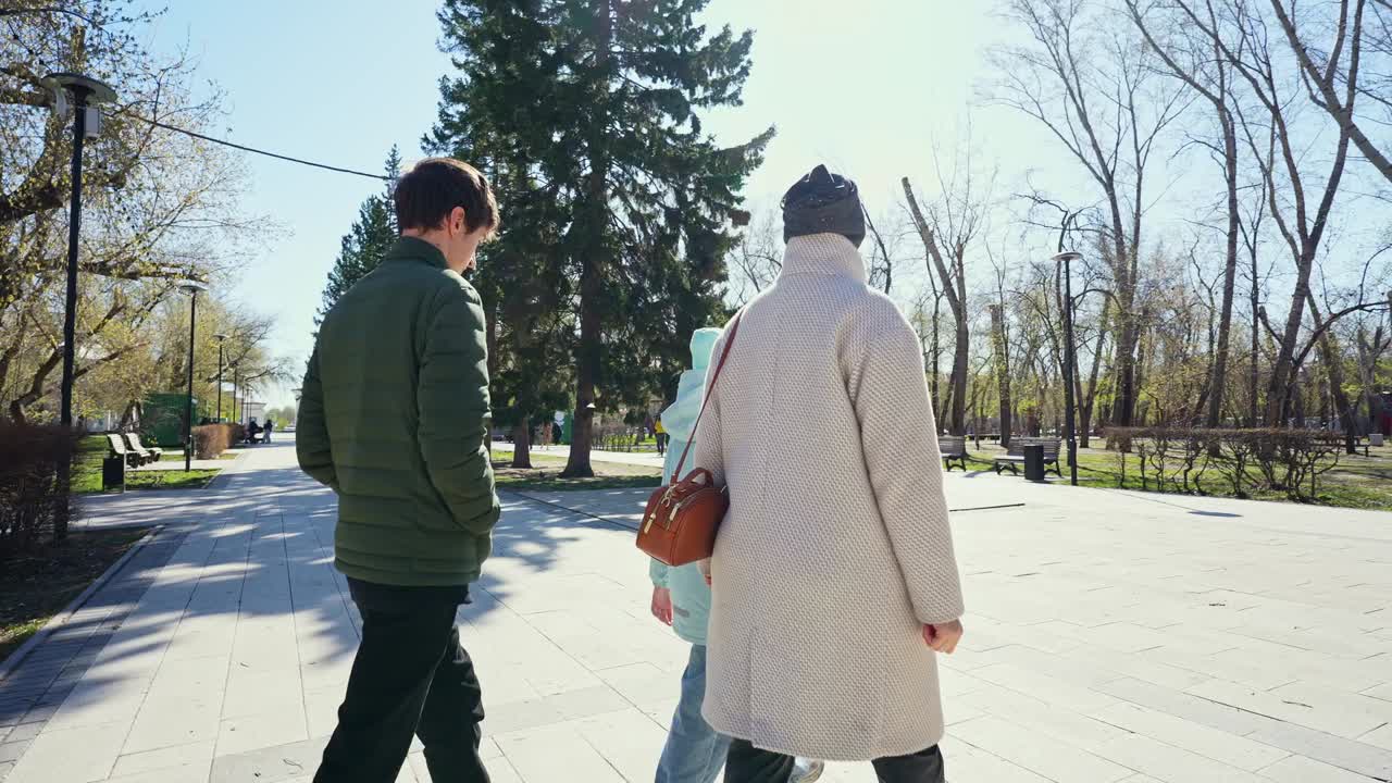 Three People Walking Together on a Sunny Day in a Park