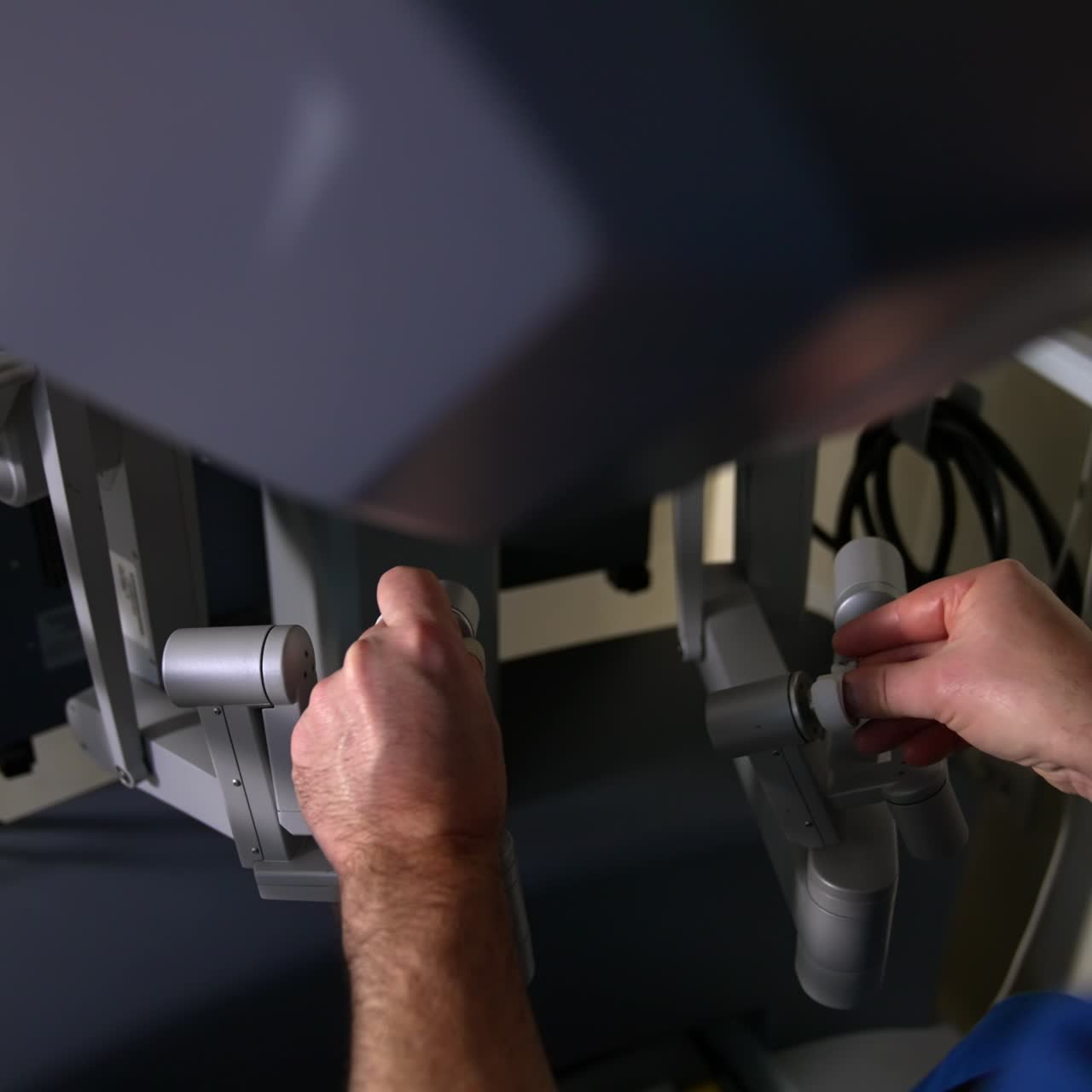 Experienced surgeon maneuvering carefully the motion controllers of Da Vinci surgical system. Close up. Top view