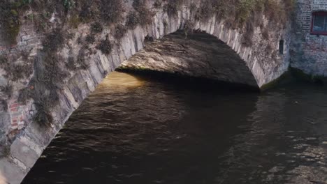stone bridge over a calm canal in bruges with soft light casting shadows beneath the arch