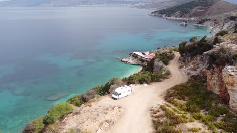 vanlife in ksamil, albania - aerial of camper van at pulebardha beach, with beautiful view of white beach and crystal blue sea