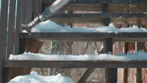 hitting ice on wooden staircase with metallic ice scrapper - wintertime day