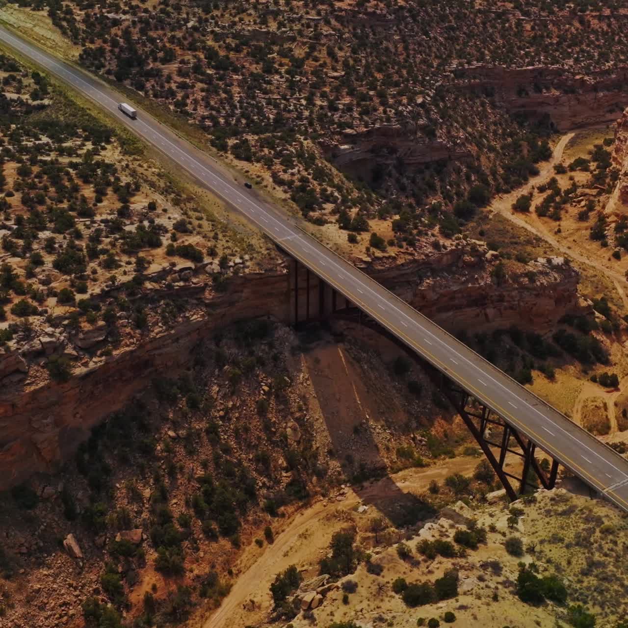 Bridges joining the sides of huge ditch in the land of a desert. Drone footage over the landscape covered with little bushes
