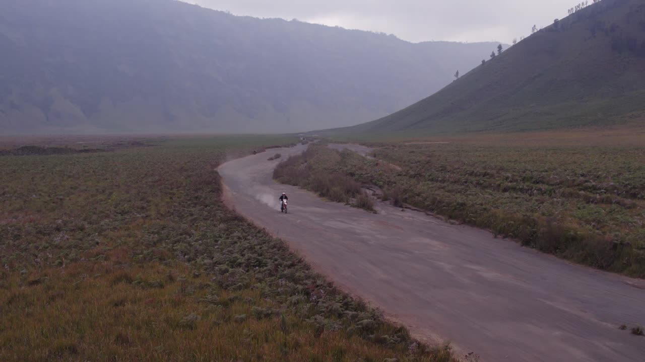 Dirt bike drives past camera at mount bromo national park, aerial