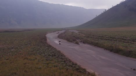 la motocicleta de tierra pasa por delante de la cámara en el parque nacional de mount bromo, aero