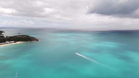 boat leaving wake on sea in deep bay beach, antigua and barbuda - aerial drone shot