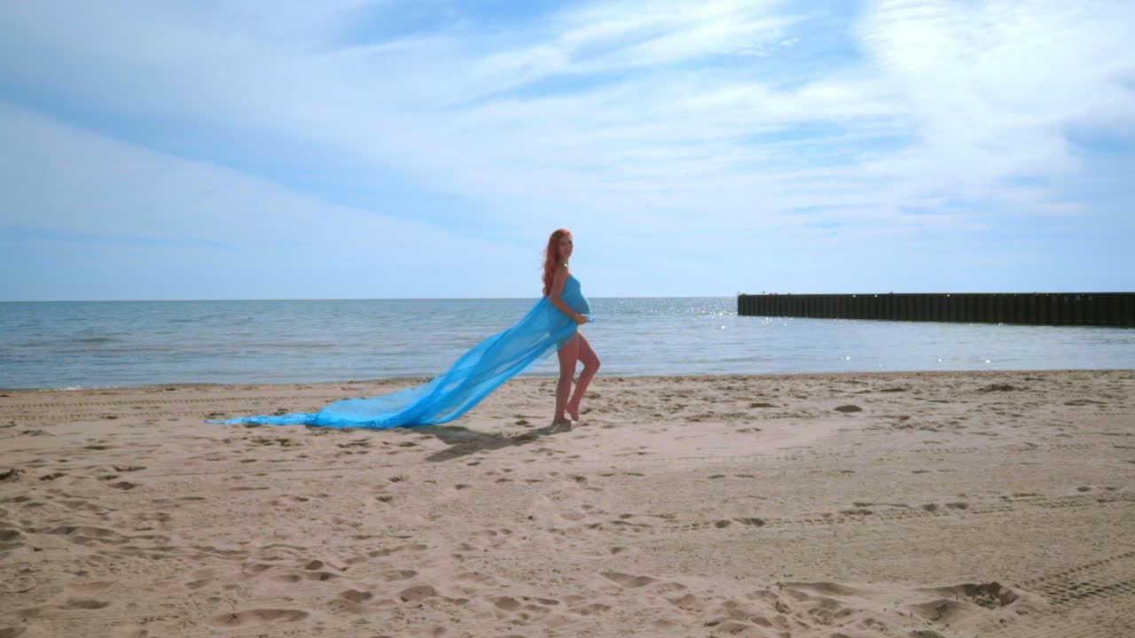 해변에서  ⁇ 만적 인 사진 세션. 바람에 파란색 천과 임신 한 커플