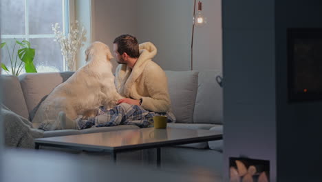 man relaxing on a cozy sofa with his golden retriever, enjoying a warm, peaceful moment