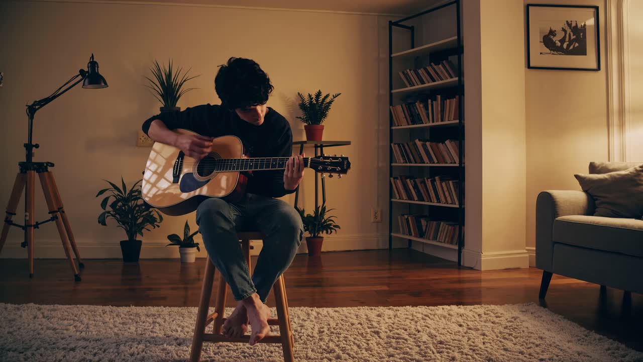 Cozy video scene of a person playing guitar in a warmly lit living room