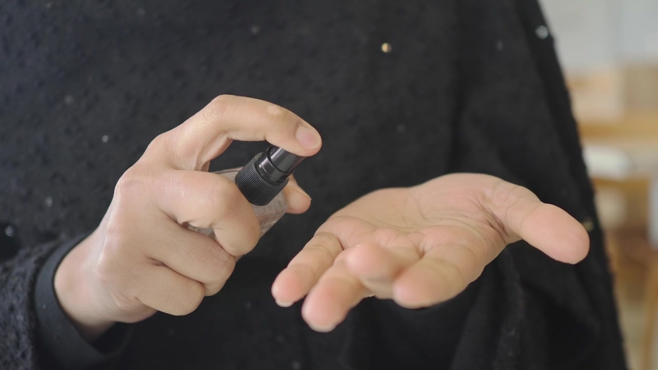 Person Spraying Hand Sanitizer onto Palm