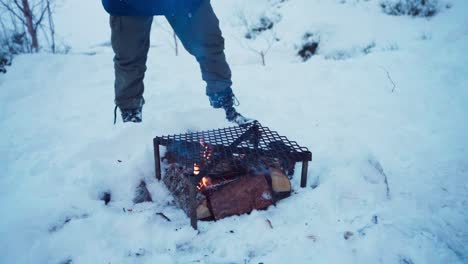 una persona está asando al aire libre con salchichas sobre leña durante la temporada de invierno