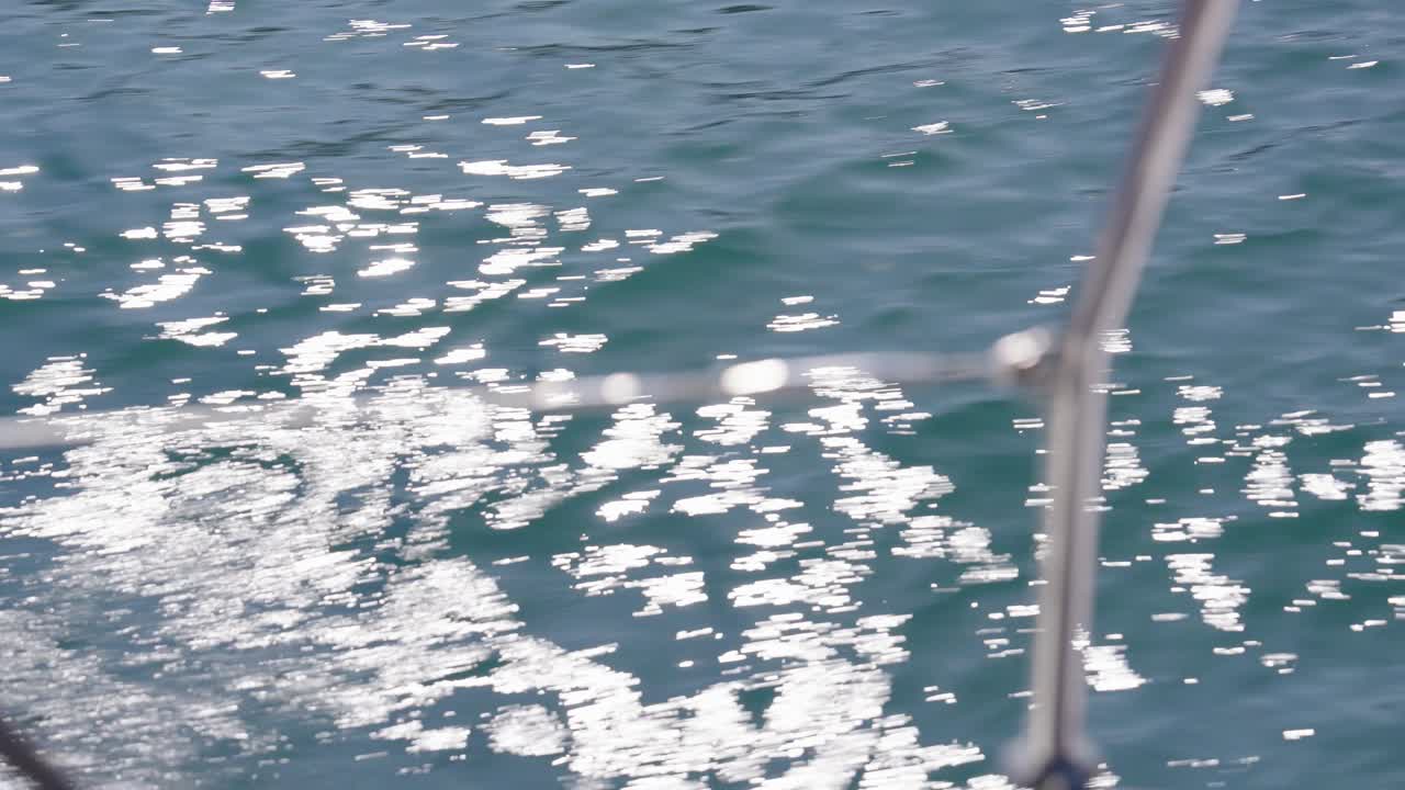 Blue water on sunny day, view through moving yachts side