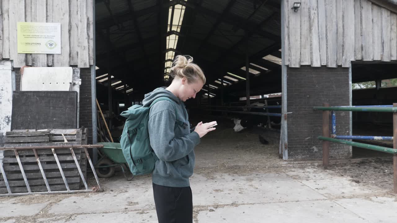 유기농 낙농장에서 휴대폰을 보고 있는 젊은 여성
