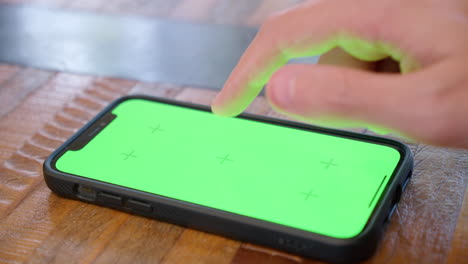 iphone lying flat on a table, screen displayed in close-up, with green screen for replacement