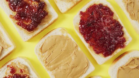 close up of multiple peanut butter and jelly sandwiches on yellow surface