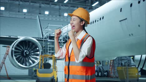 mujer ingeniera emocionada celebrando en el hangar de mantenimiento de aviones