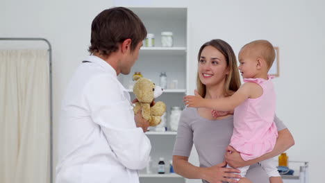 doctor giving a teddy bear to a baby