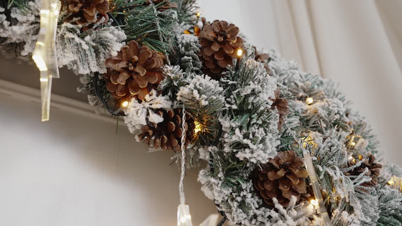Verschneiter Weihnachtskranz mit Lichtern und Tannenzapfen