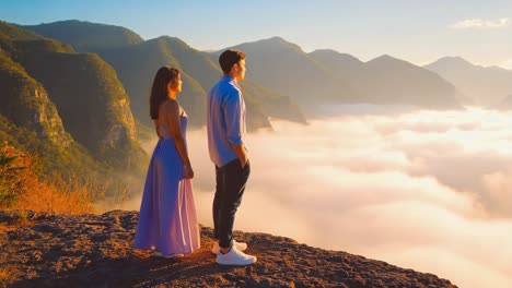 young couple standing on a mountain peak, savoring a breathtaking sunrise illuminating a sea of clouds, enveloping the scene in a serene and romantic atmosphere filled with tranquility