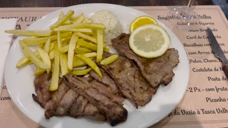 static view of a meat dish with rice, fries and lemon. restaurant