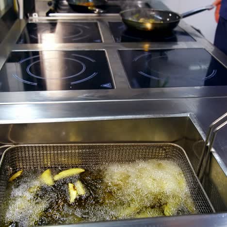frying potatoes in a restaurant fryer basket. french fries. junk unhealthy fast food preparation. tasty unhealthy food