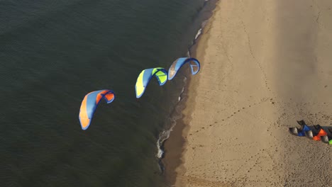 Drone-Aéreo-Orbita-Alrededor-De-3-Cometas-De-Kitesurf,-Kitesurf