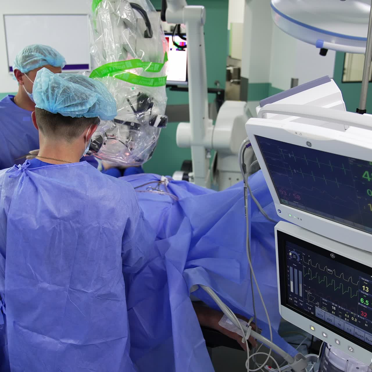 Team of male surgeons conducting surgical operation. Modern equipment surrounding medics in well-equipped operational theatre