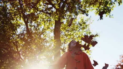 girl throwing leaves in park